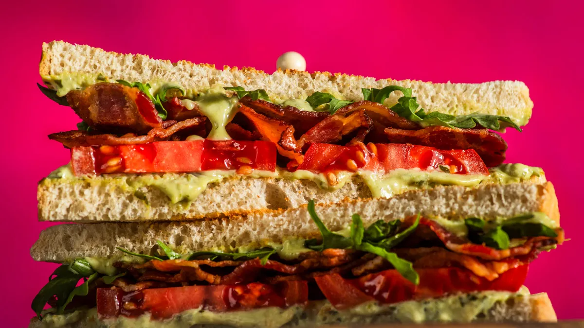 a sandwhich with tomato, bacon and herbs inside