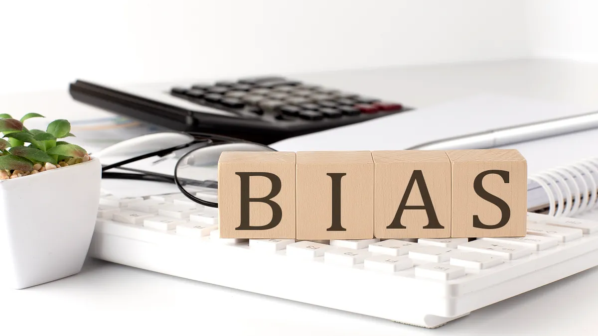 BIAS written on a wooden cube on keyboard with office tools