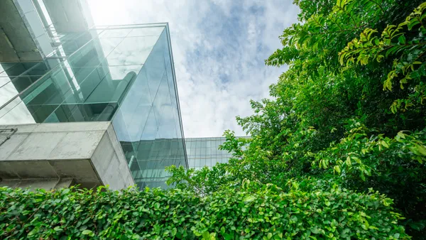 A modern office with glass windows looking over a green outdoor courtyard.