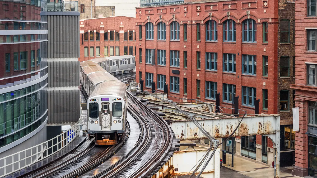 An above-ground train snakes through buildings in an urban downtown