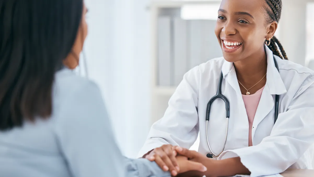 Happy doctor, holding the hands of a patient