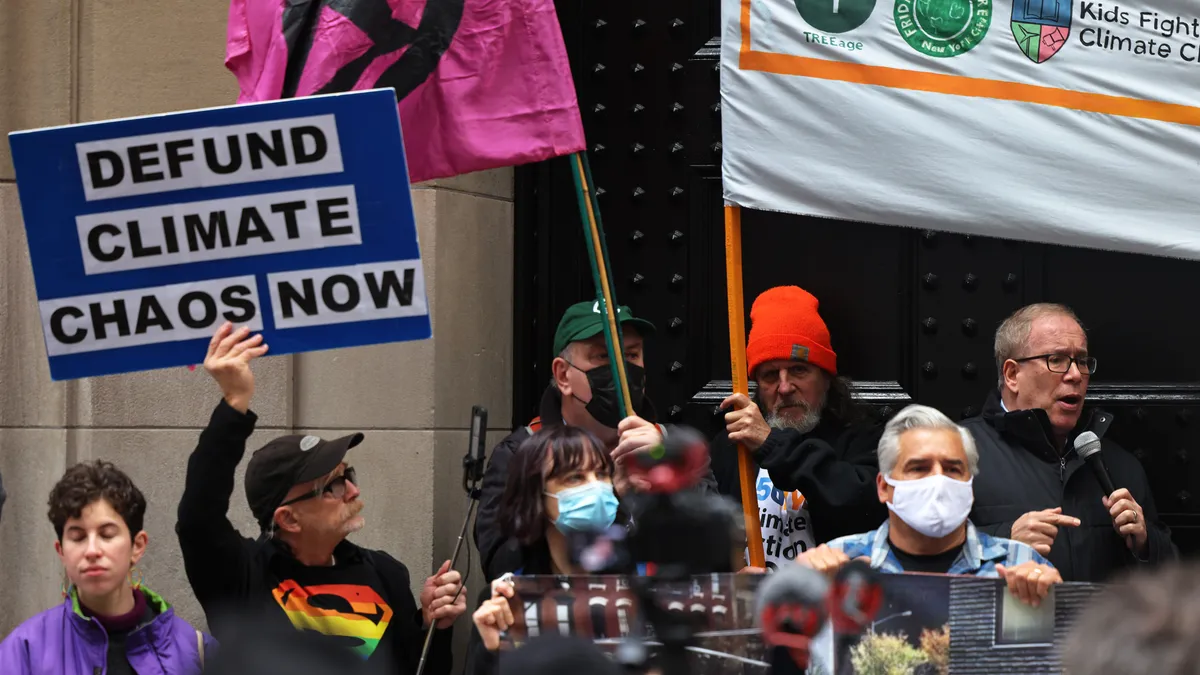 People hold signs and flags calling for action to address climate change.