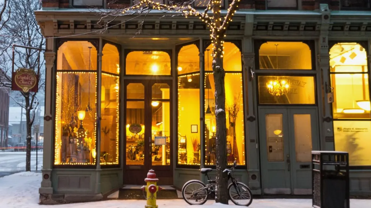 A corner store at dusk during winter, with a bike out front in the snow.