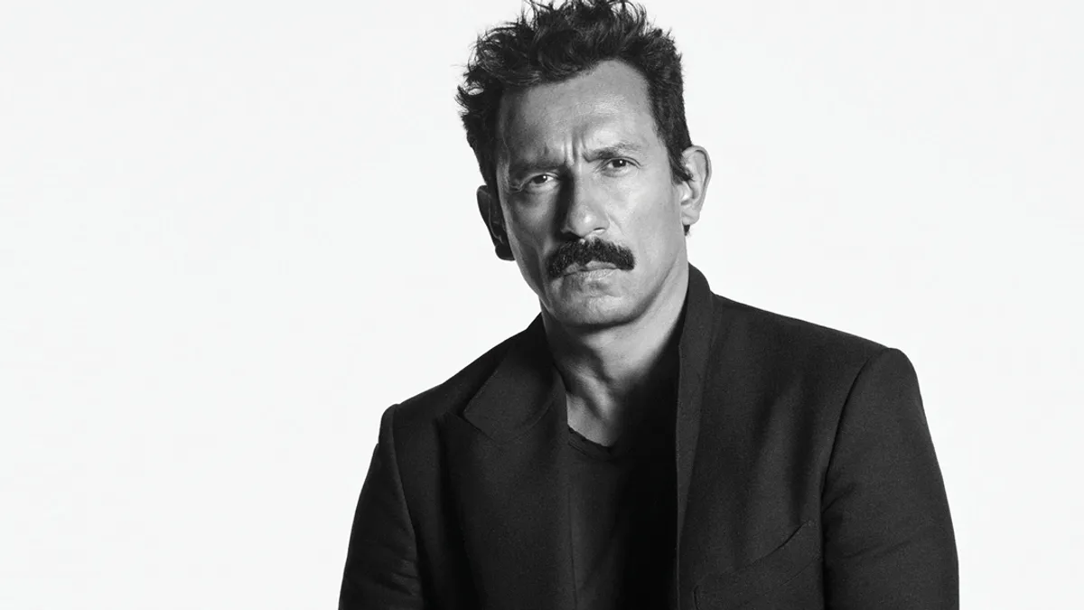 Haider Ackermann stands for a professional headshot in black and white.