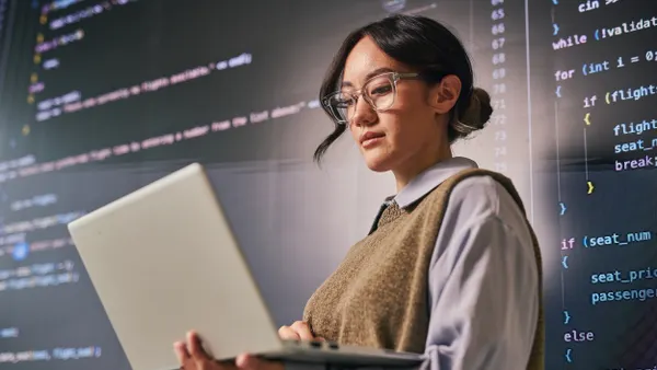 Young woman reviewing code on a laptop
