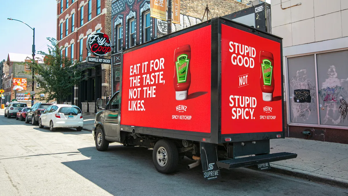 An out-of-home ad placed on the side of a truck promoting Heinz' spicy ketchup as part of its "Stupid Good, Not Stupid Spicy" ad campaign.