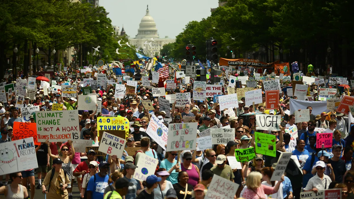 Climate protesters line the street with the Capitol in the background.