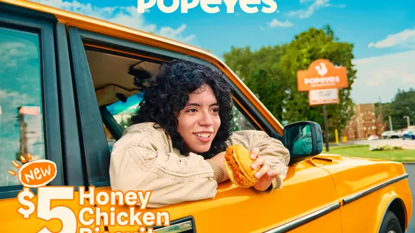 A woman in a car holds a chicken sandwich.
