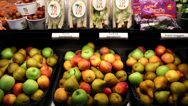 Fresh fruit and other food items are in a case accessible to students at a school cafeteria.