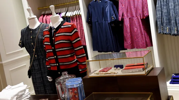 The interior of a Draper James store. Clothes are folded on a table and hanging on display.