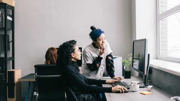 Colleagues helping each other on the computer at work