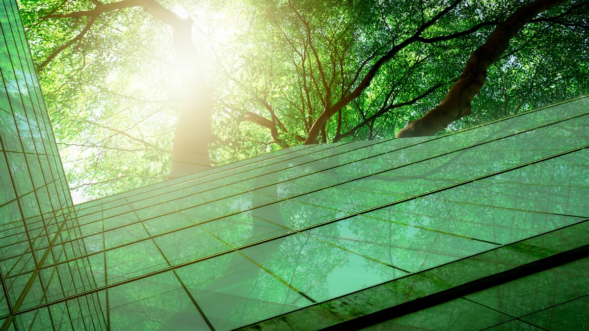 Sustainable glass office building with trees for reducing carbon dioxide.