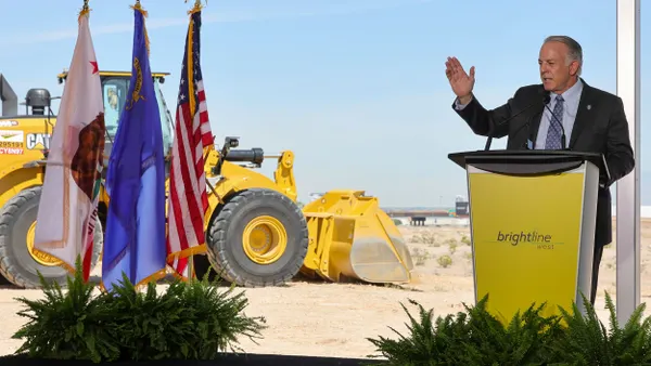 Man in suit at podium on a construction site.