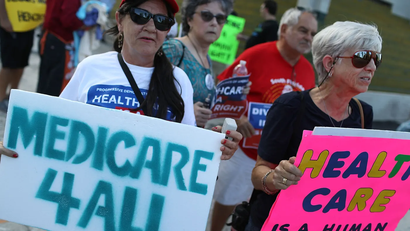 protestors hold up signs advocating for universal healthcare