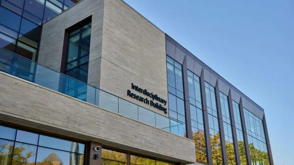 An image of a gray stone building beneath a blue sky. On it reads "interdisciplinary research building."