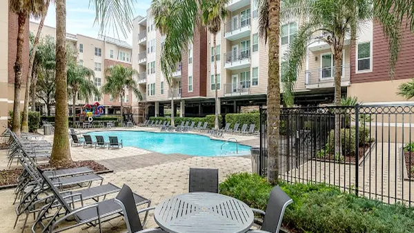 Palm trees, deck chairs and apartments surrounding a pool.