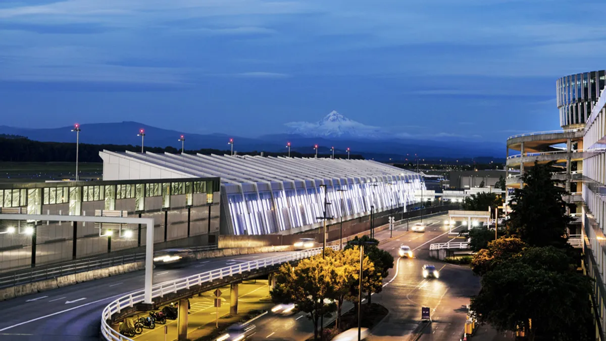 Cars approach a well lit airport loop.