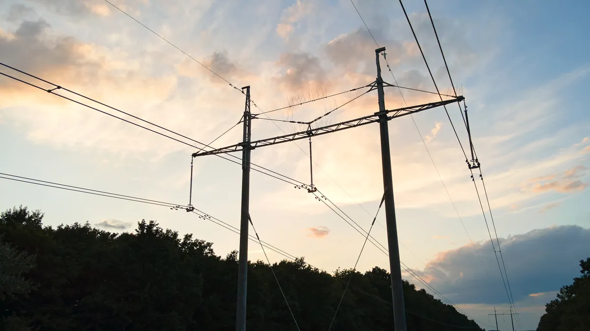 High voltage tower with electric power lines at sunset.