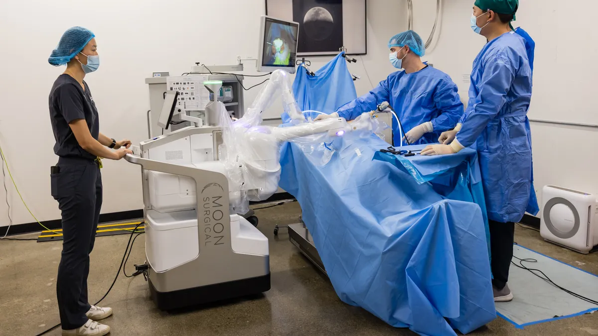 Moon Surgical's Maestro robot is displayed in an operating room, accompanied by three clinicians.