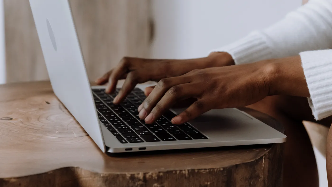 A Black person types on a laptop