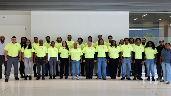 A group of people, many in yellow shirts, pose for a photograph.