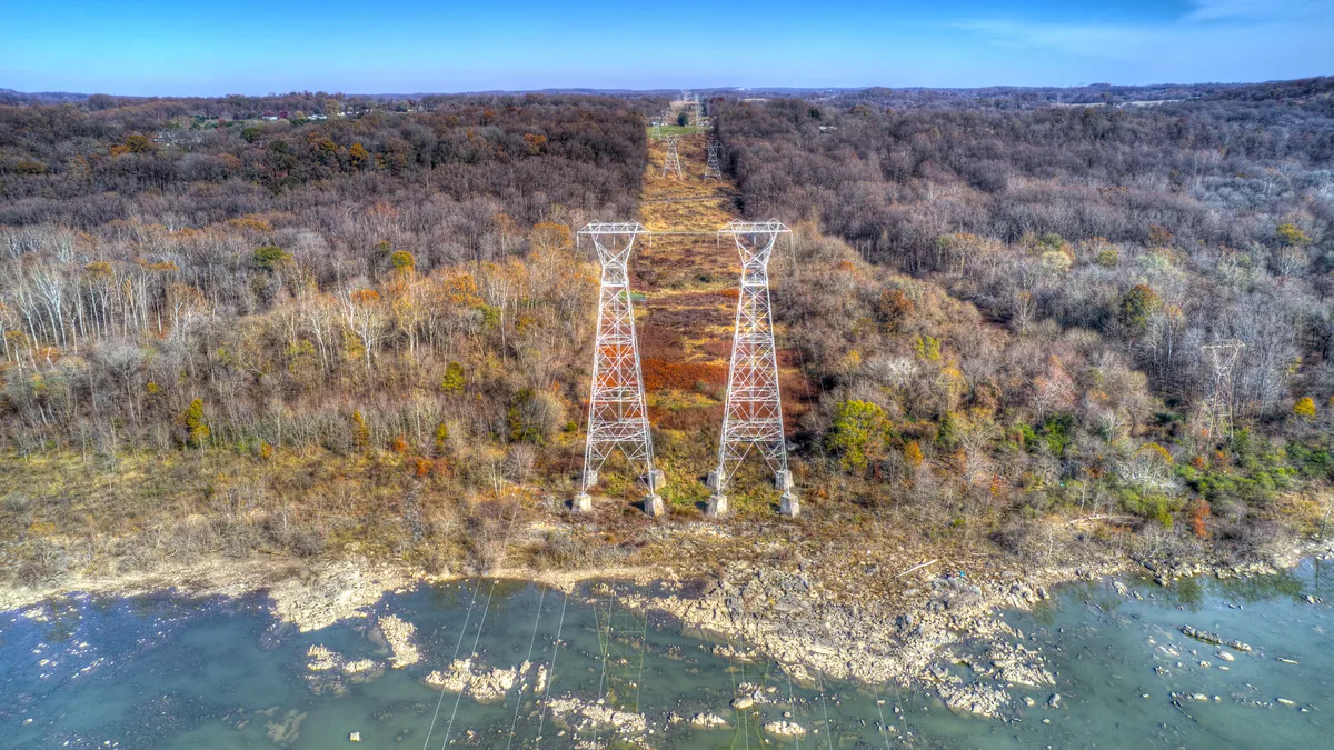 Aerial View of High Tension Power Lines Cutting Through Woods with Fall Colors.