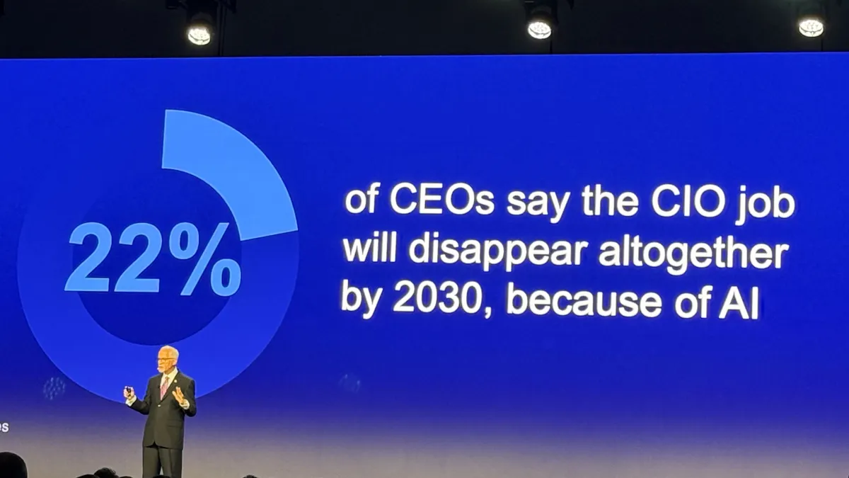 Gartner VP analyst David Furlonger speaks on stage in front of a PowerPoint presentation on a blue screen.