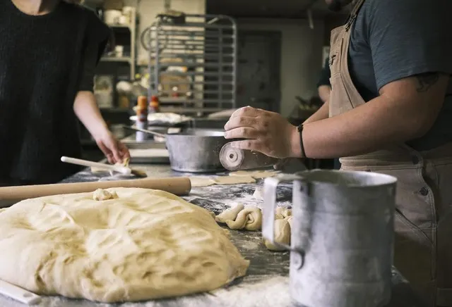 We see hands working dough in a commercial-style kitchen.