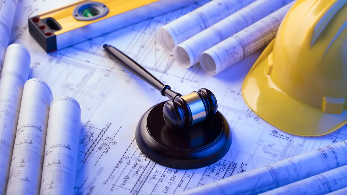 A photo illustration shows a judge's gavel among construction blueprints.