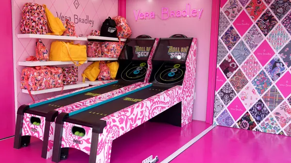 A colorful, floral pink room display features tote bags and games.