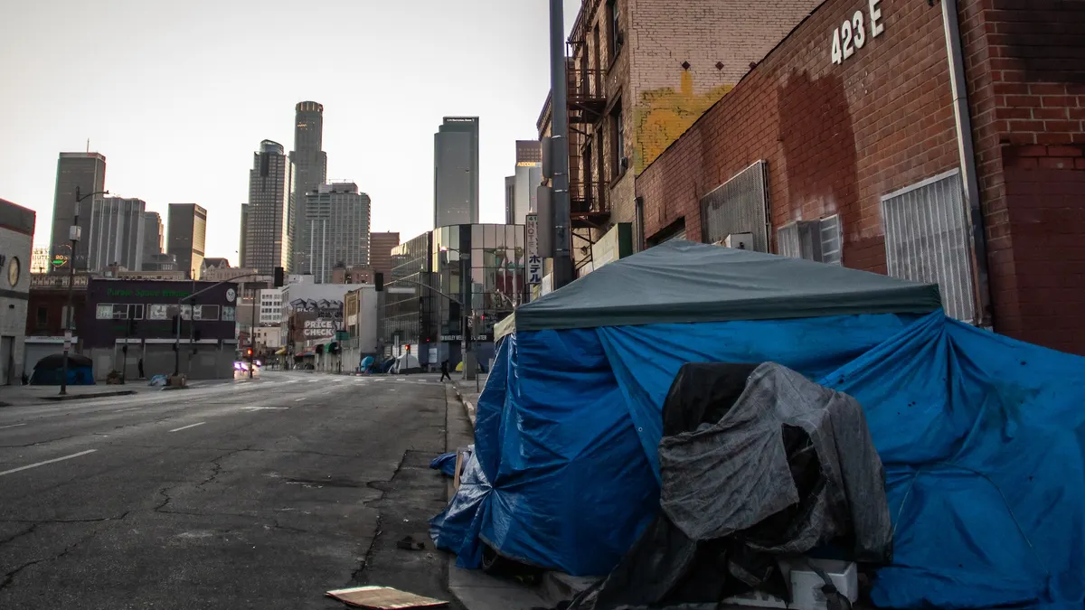 A blue tent on a city street with a view of skyscrapers in the background