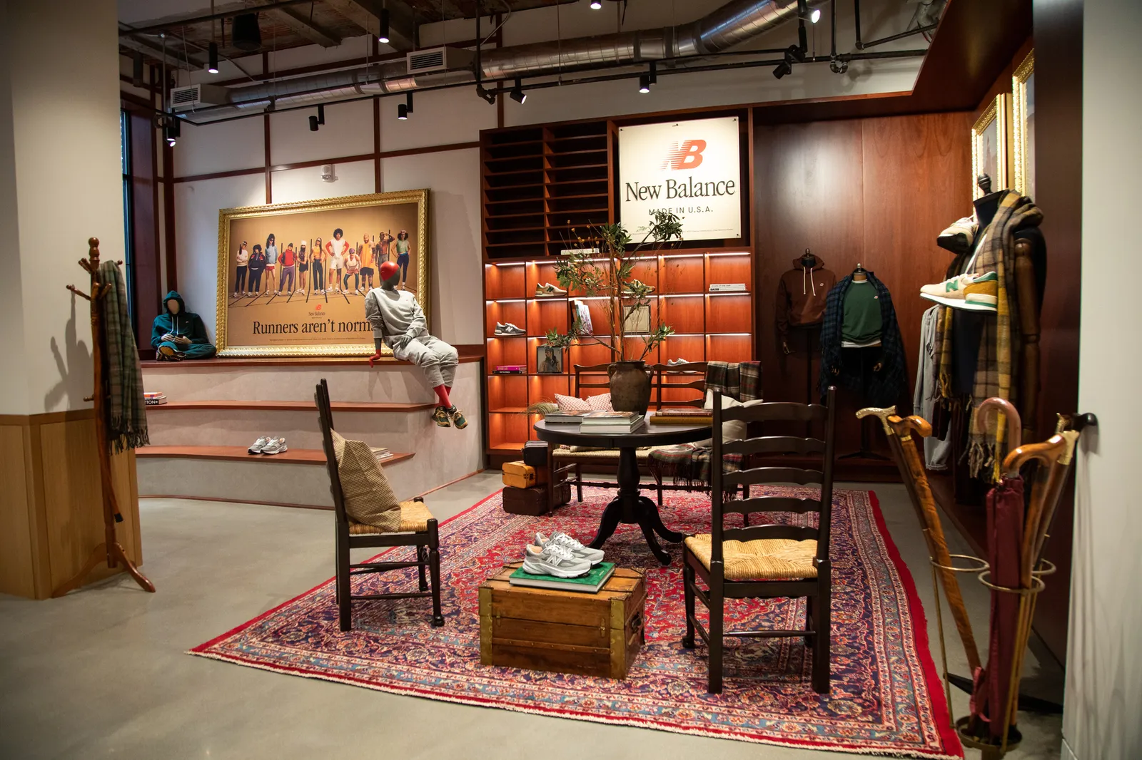 Interior of a New Balance store with mannequins sitting on stairs and wooden shelving and seating