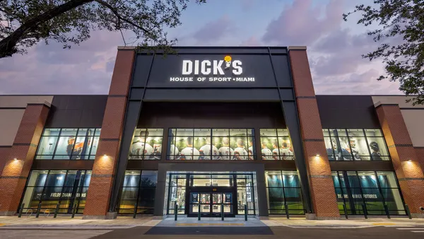 A green and red brick Dick's storefront with trees in the foreground.