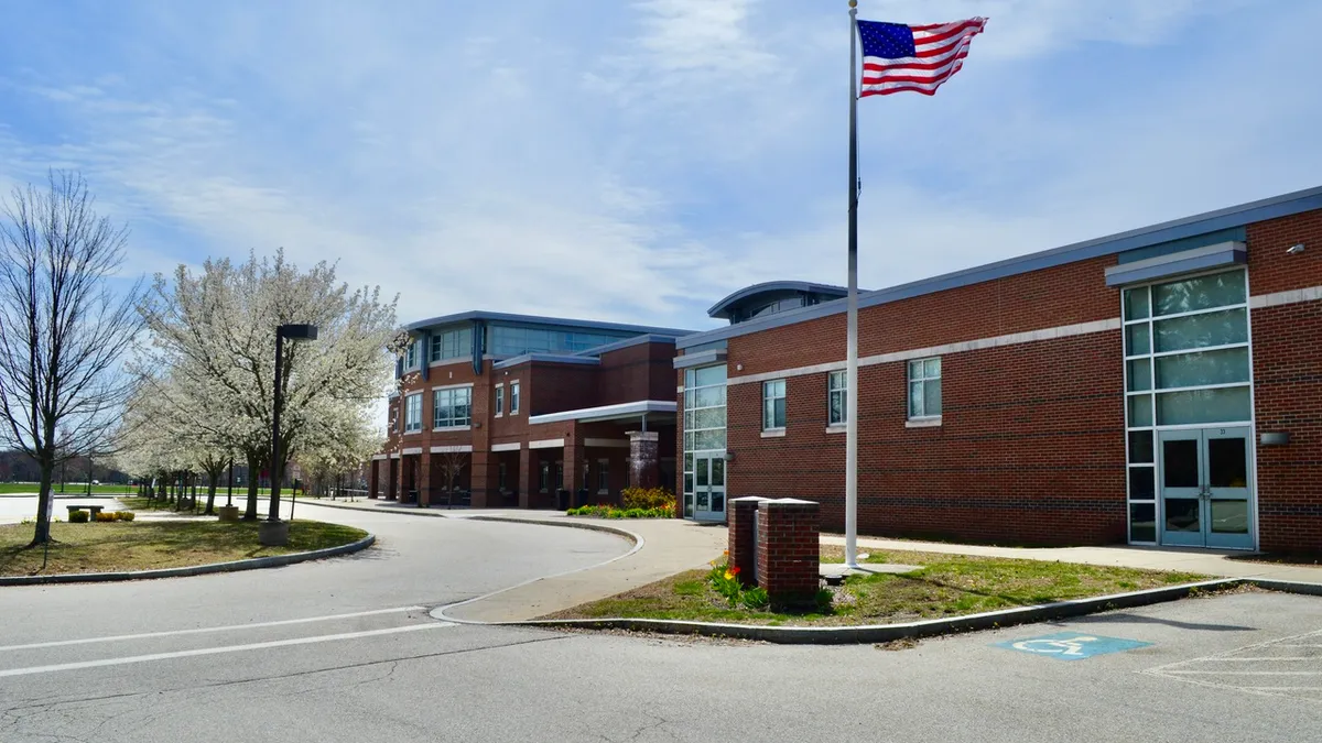 Facade of Hingham High School against a blue sky with an American flag in the foreground