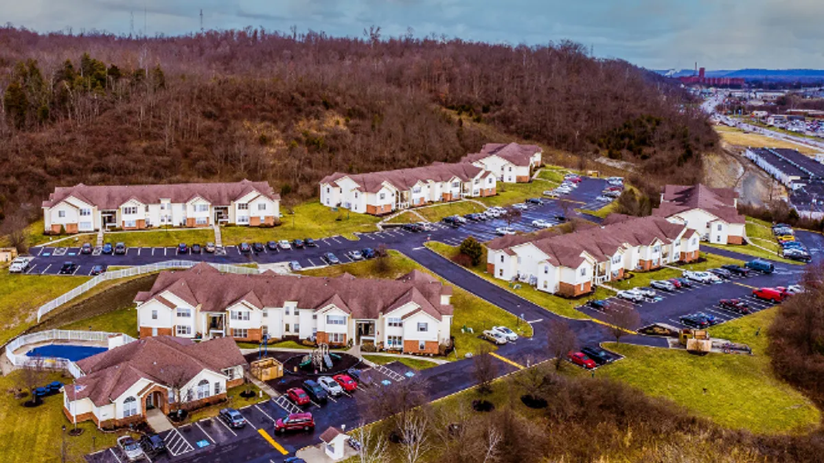 Aerial view of apartment community with trees in the background.