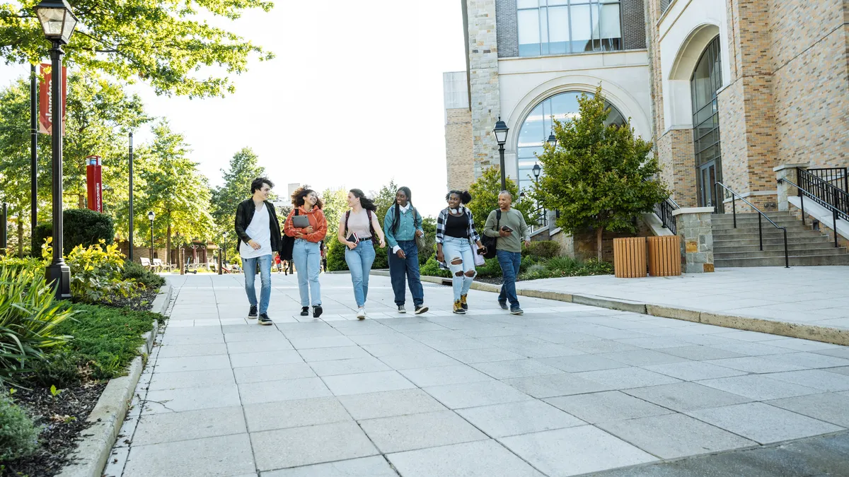 Group of diverse Hispanic, American and African students in campus outdoors, walking together and talking.