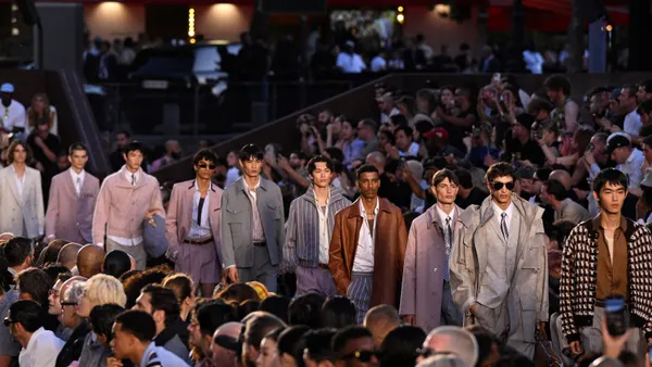 Male models walk down a fashion runway.