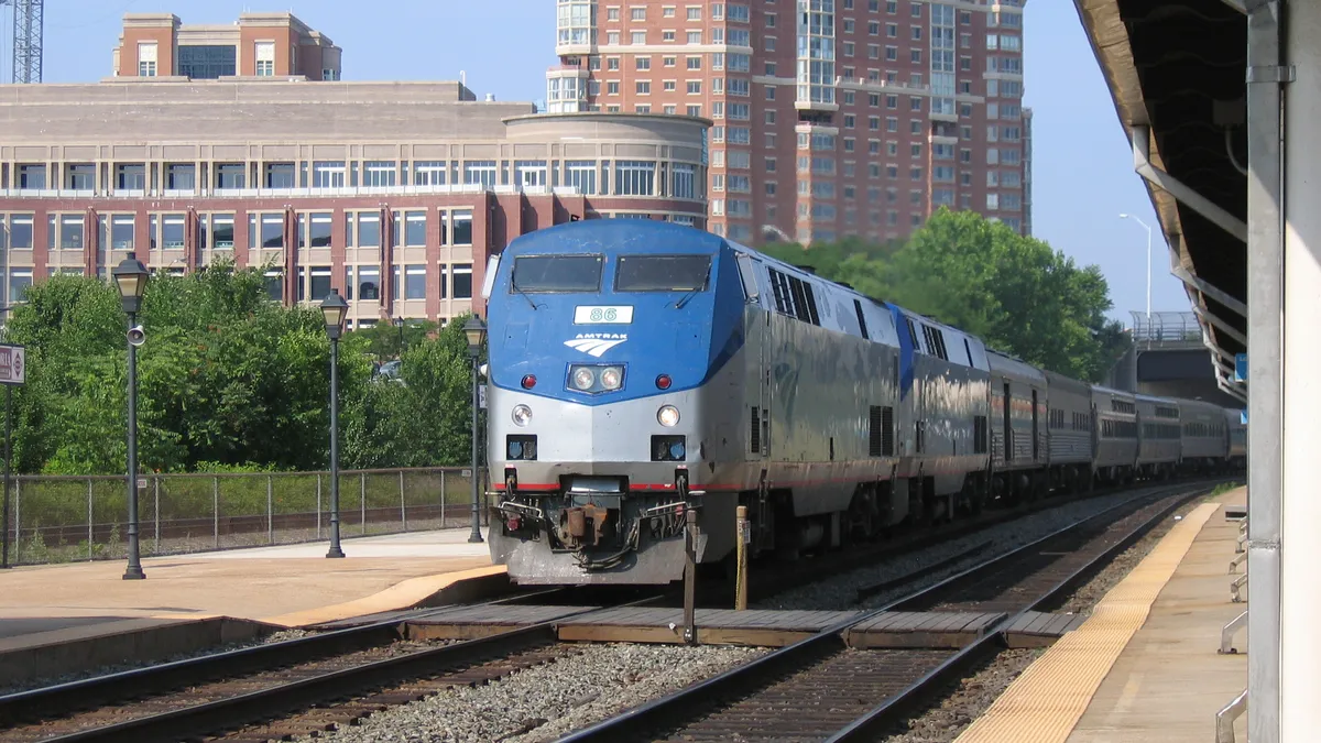 An Amtrak locomotive pulls a passenger train into a station.