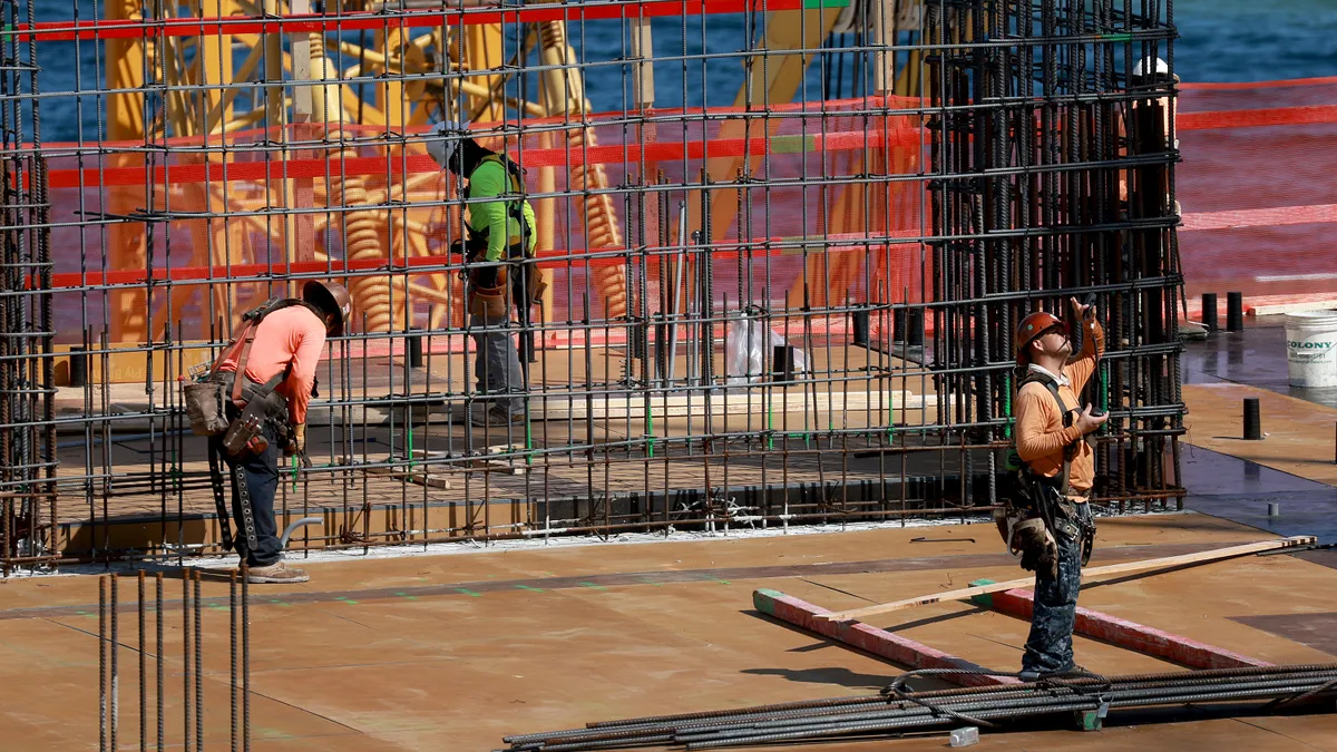 Construction workers surrounded by material work on a roof.