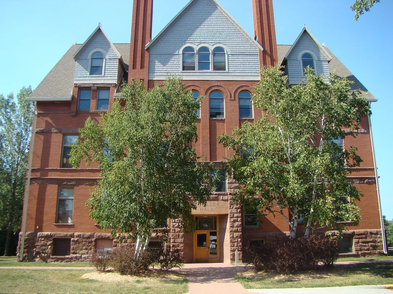 Large brick and stone building with dormer windows with blue sky in top background.