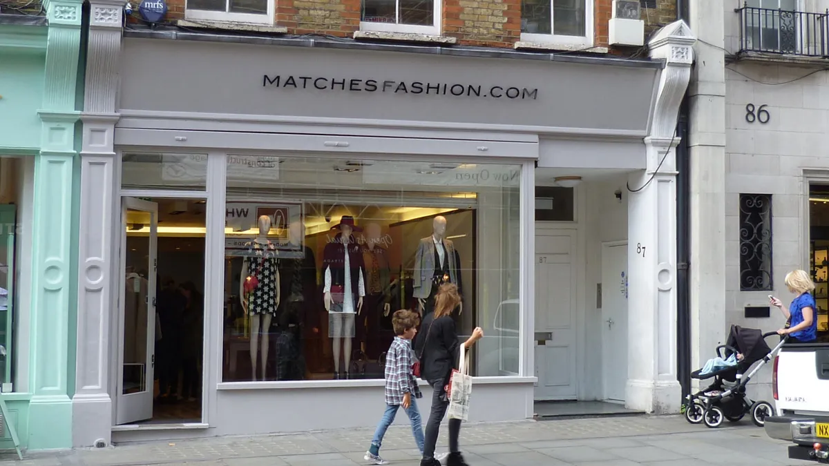 Multiple people walk in front of a Matches storefront. The window display shows three mannequins.