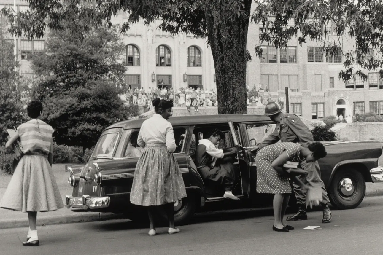 Black women step out of a vehicle with the help of a National Guardsman