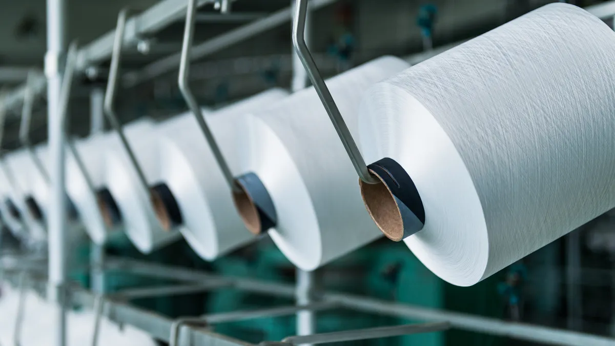 Spools of yarn are lined on a spinning machine.