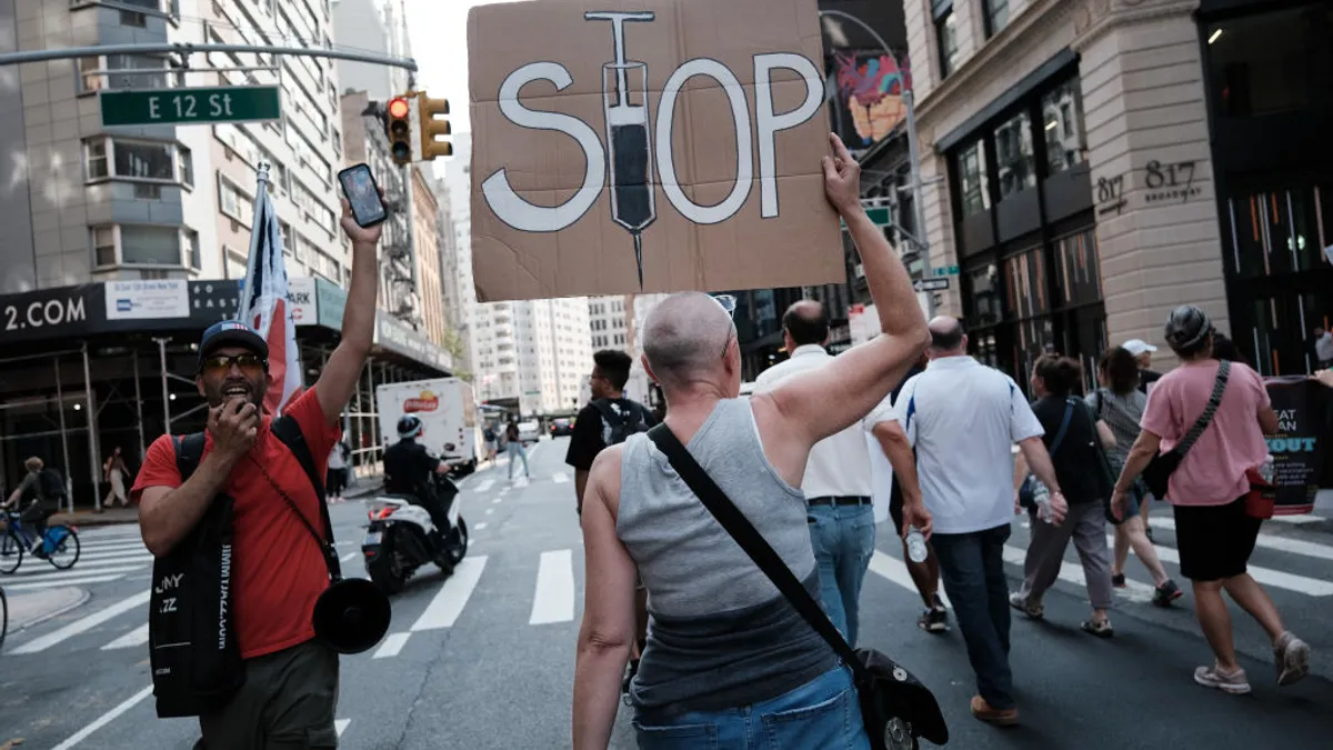 anti-vaccine protestors with a stop vaccines sign on street