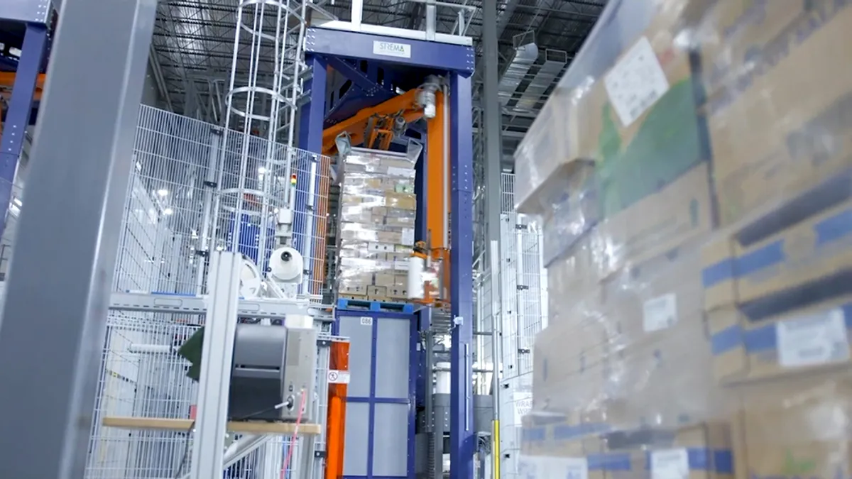 A stack of cardboard boxes are wrapped in plastic in a machine.