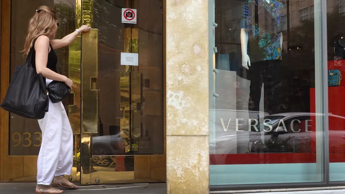 A shopper in a black tank top and white pants enters a Versace store in Chicago, Illinois.