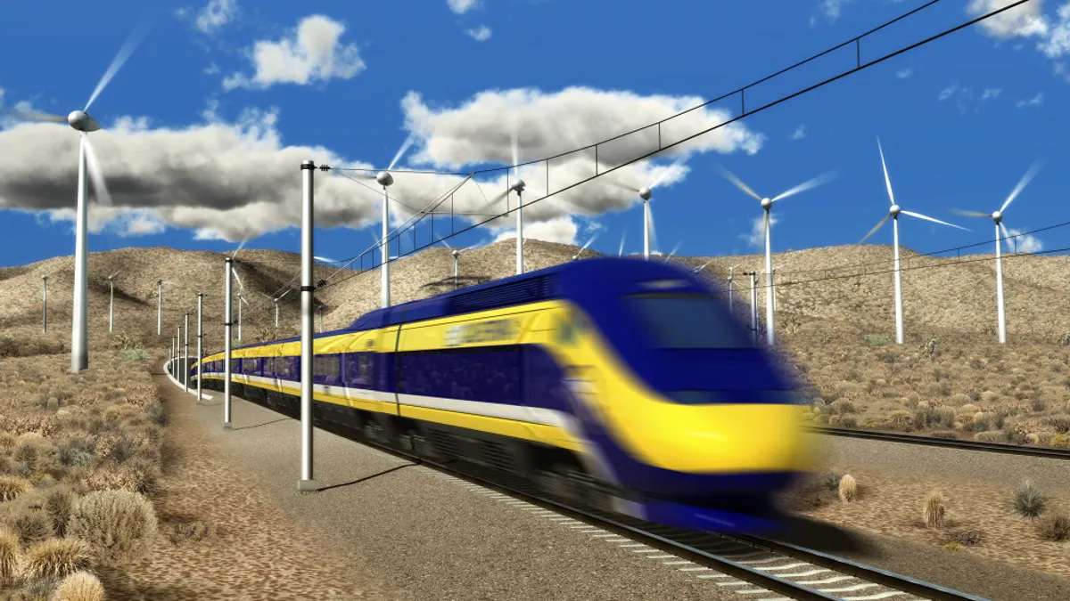 A sleek yellow and bluish purple train whizzes through the desert between tall white wind turbines in this rendering.