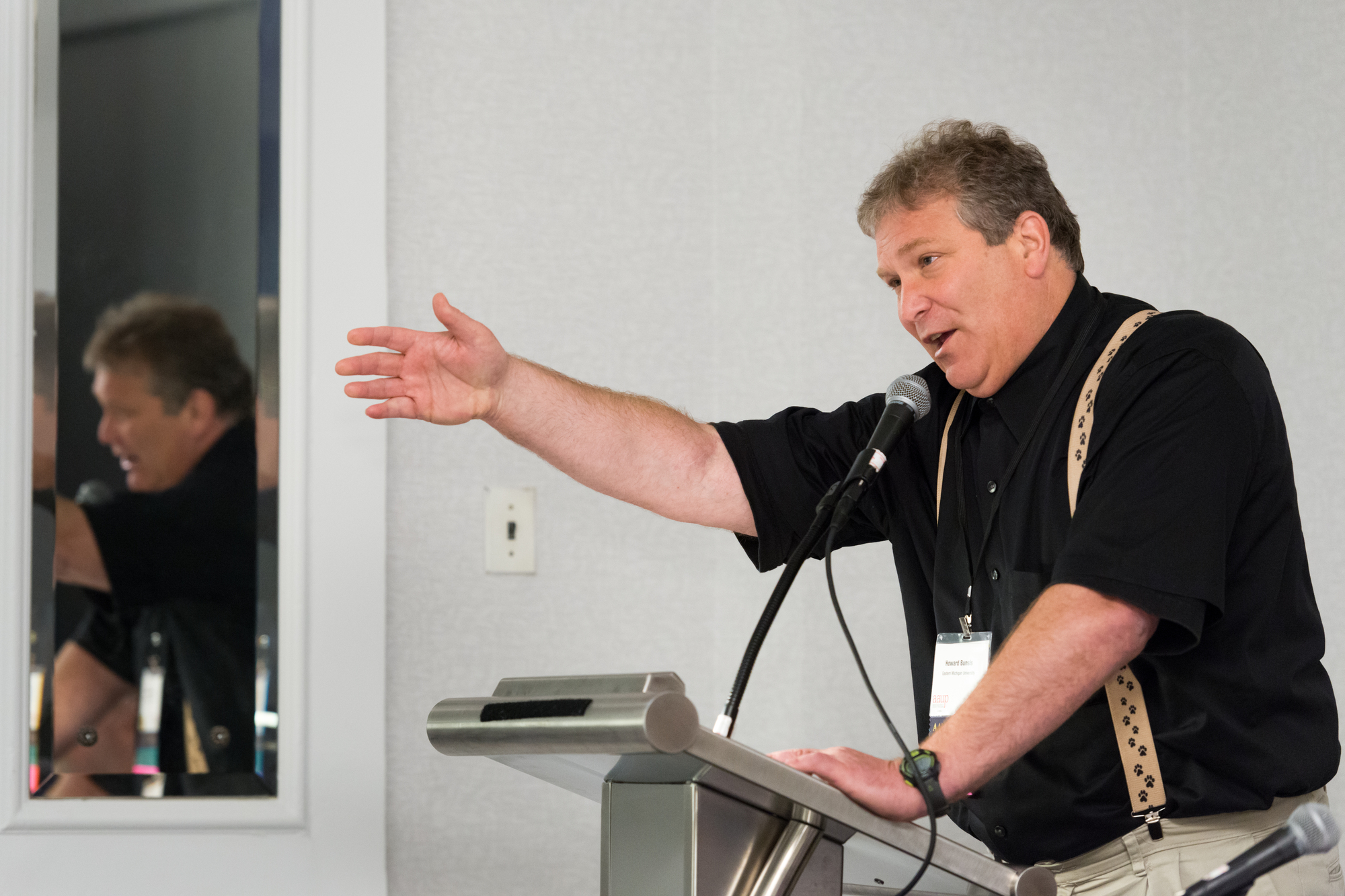 Howard Bunsis speaks at a podium with one arm outstretched.