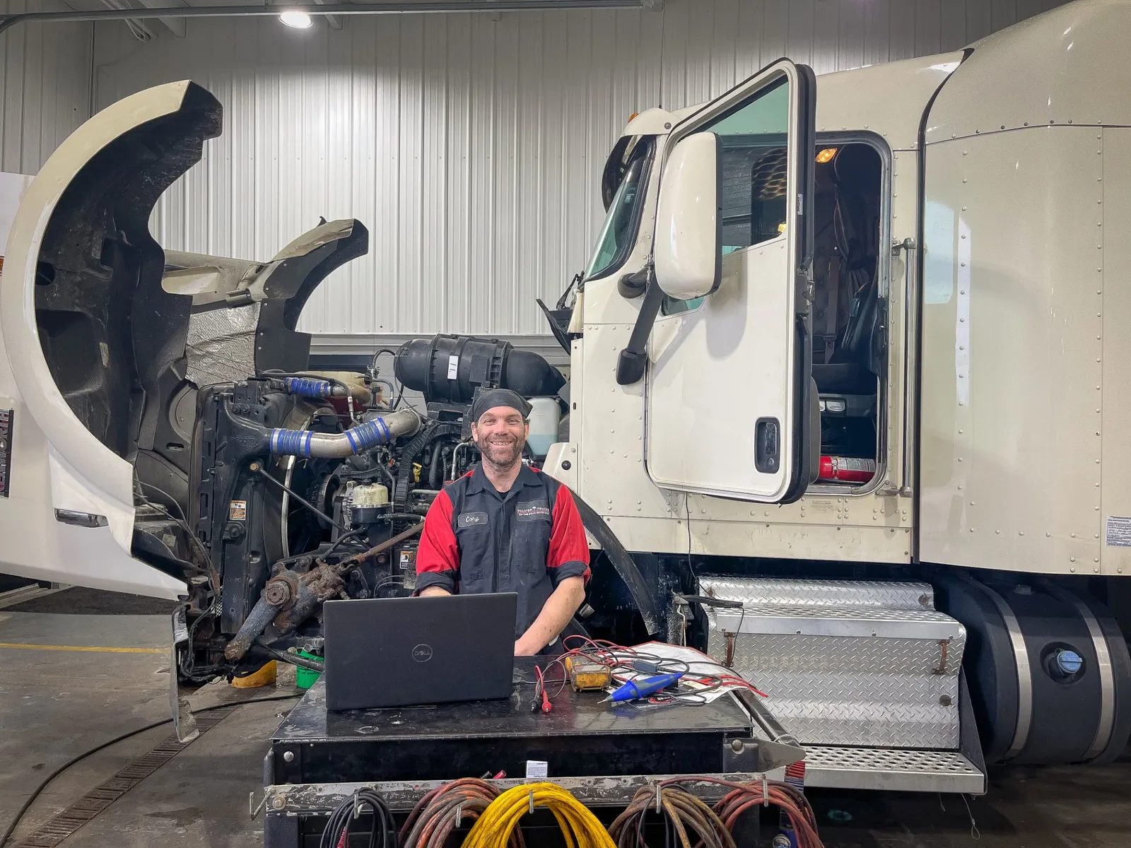 A Palmer Trucks staffer smiles at the camera in front of a truck being serviced.