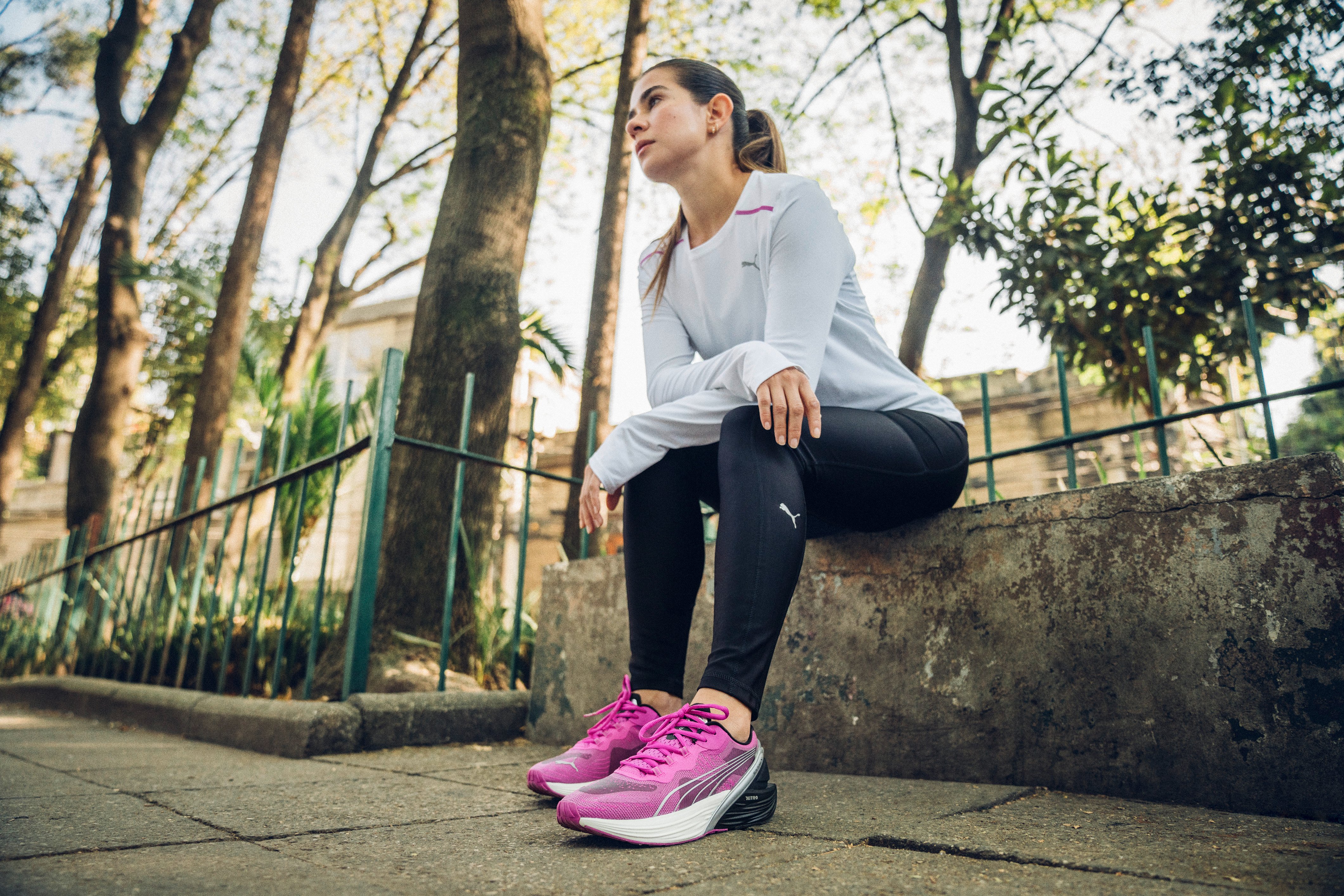 A woman in Puma running shoes sits on a bench.